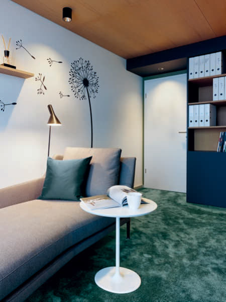 Die Erholungszone bildet das Sofa von B & B Italia, ergänzt mit einer Stehleuchte von Louis Poulsen, einem Beistell- tisch von Arper, Wandregalen und dekorativem Wandtattoo.