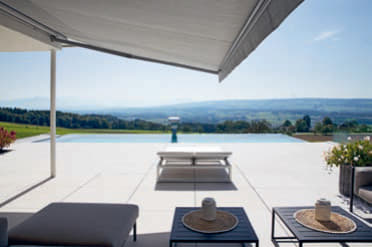 Die Terrasse bietet eine Aus- sicht über den Pool bis hin zu den Bergen.
