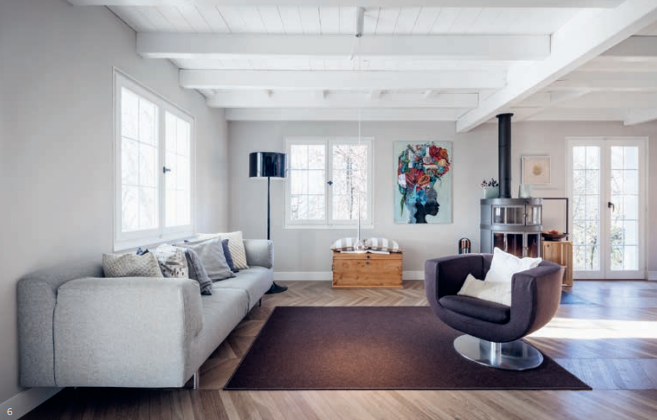 Mit wenigen Möbeln ist der Wohnbereich gemütlich eingerichtet. Der Teppich sowie der Sessel in gleicher Farbe grenzen diesen Bereich von der Küche ab.