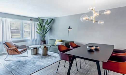 Erdtöne vereinen den Wohn- und Essbereich und strukturieren ihn, wobei der Teppich von Jacaranda eine Insel für Sofa, Sessel und Beistelltische kreiert.