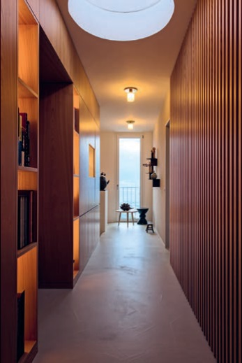 Kastanienholz zieht sich als roter Faden durch die Wohnung und verwandelt den Korridor in eine kleine, aber feine Bibliothek.