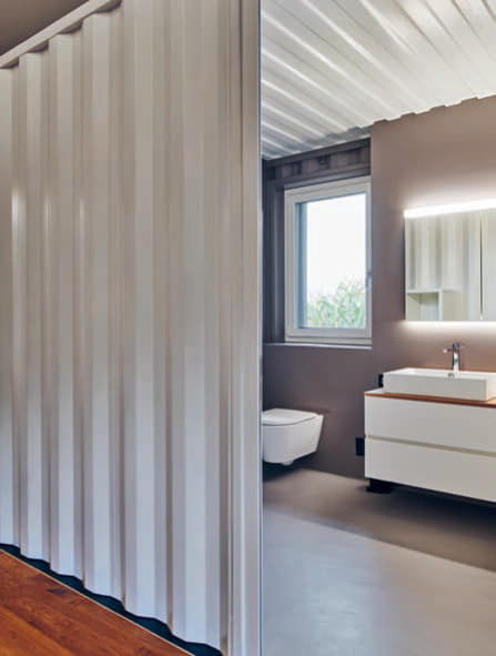 Der graue Gussboden und die gleichfarbige Wand verschmelzen mit der grauen Containerinnenwand in diesem Badezimmer.