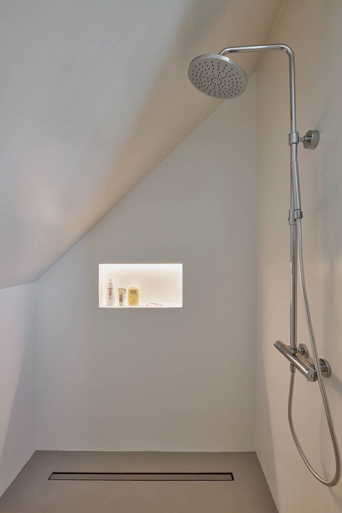 Moderne Dusche welcher von der schrägen Decke in der Höhe limitiert wird.