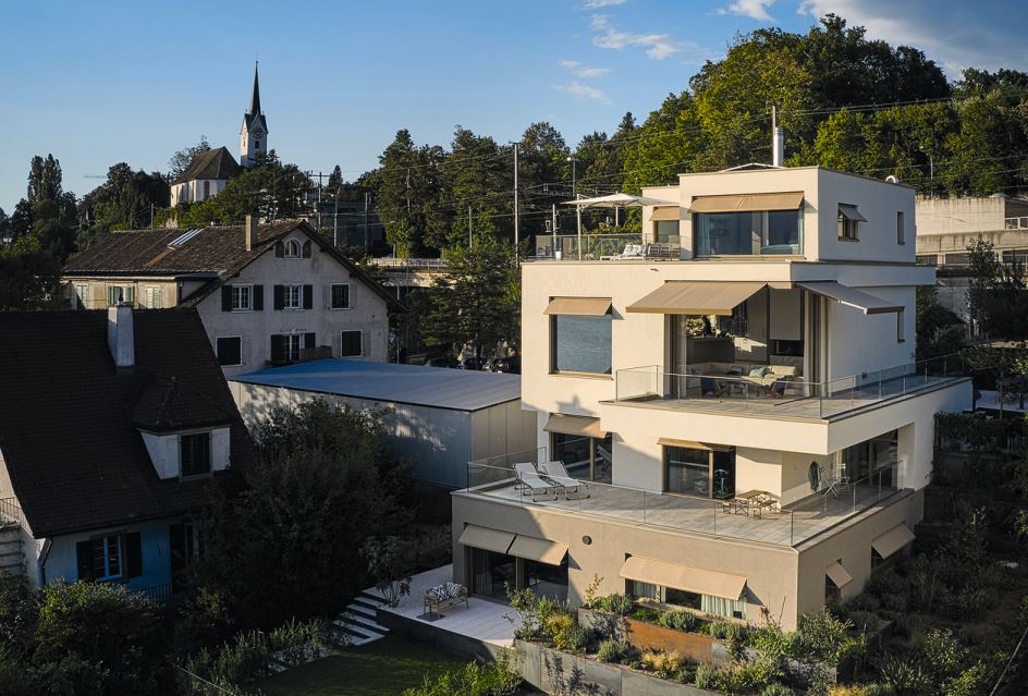 Alles Überirdische ist in Off-white mit kupfernen Fensterrähmen und -bänken, deren Farbe mit dem Braungrau des Sockels spielt. Durch die farblich abgesetzte Einliegerwohnung wirkt das Haus nicht wuchtig.