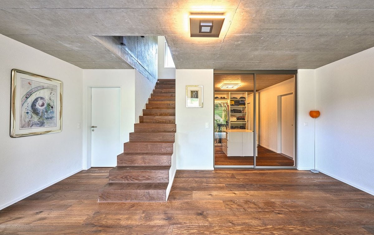 Die Treppe ist mittighaus und dient mit den Sichtbetonwänden als Raumtrenner zwischen Wohnen und Essen.