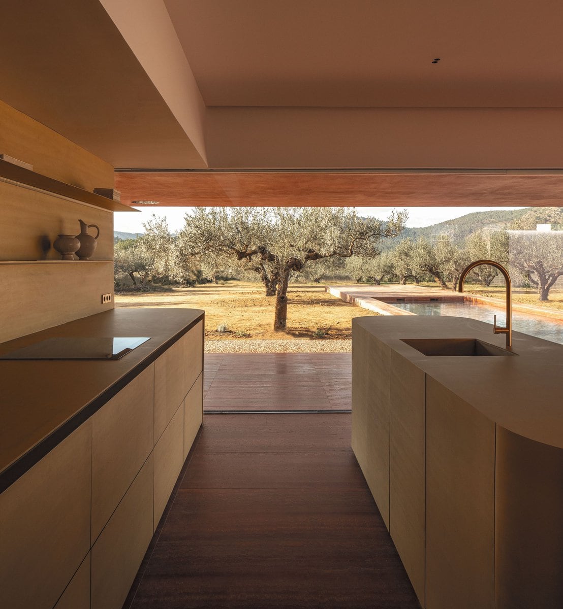 Die bronzefarbene Küche ist der Blickfang des Hauses. Zwischen harmonischen Materialien, Farben und Textilien setzt die Kücheninsel ein Statement.