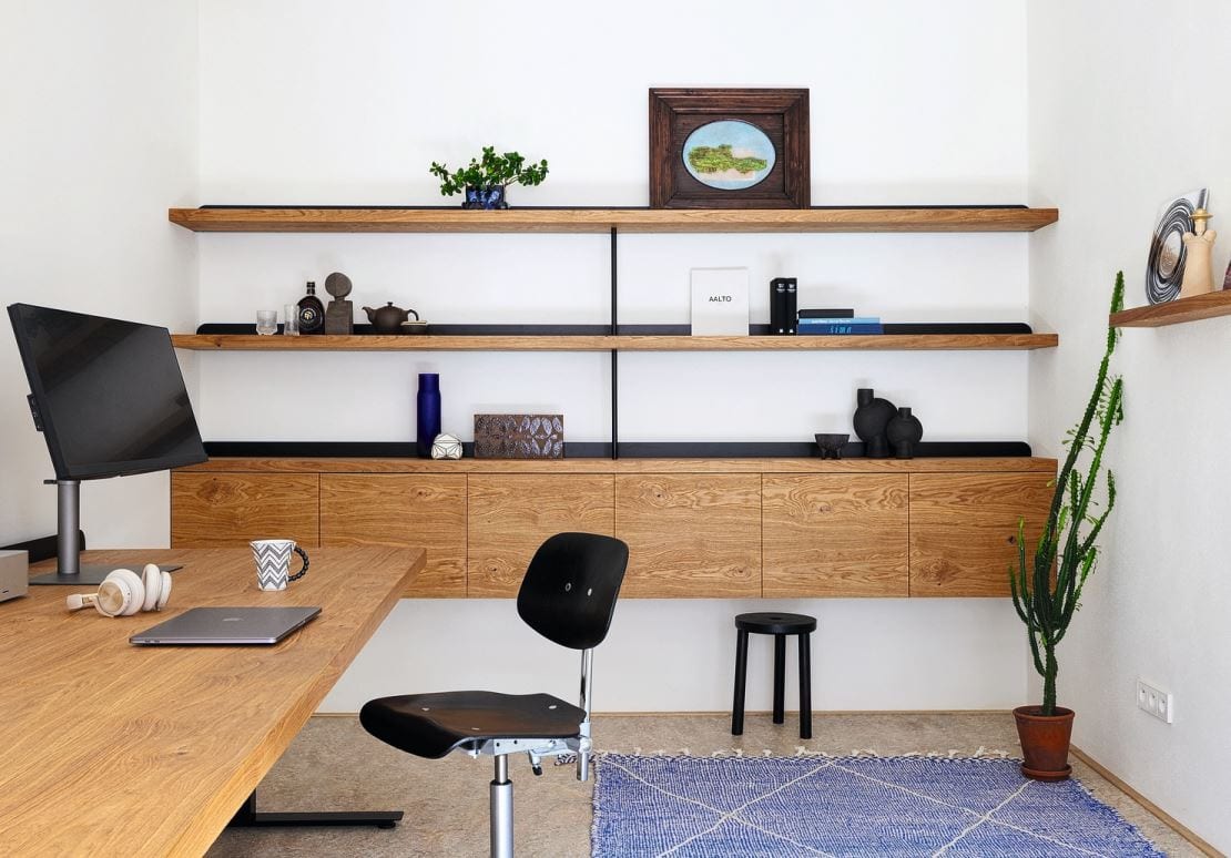 Massgeschneiderte Möbel wie dieses Wandregal und harmonische Materialien schaffen eine ganzheitliche Wohlfühlatmosphäre – auch im Büro.