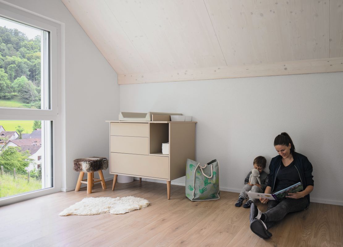 Behagliches Kinderzimmer im Obergeschoss mit sichtbarer Holzdecke.
